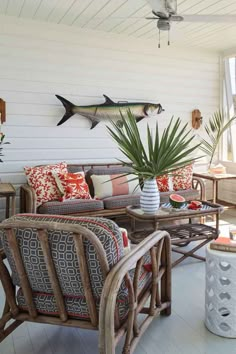 a living room filled with furniture and a fish wall hanging on the wall above it