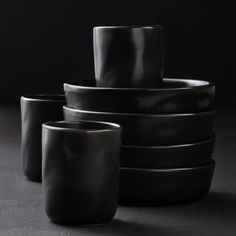 a stack of black cups sitting next to each other on top of a gray surface