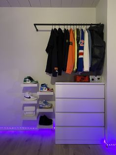 an organized closet with white drawers and blue lights on the floor, along with shoes