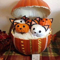 three cats in a pumpkin shaped basket on a table