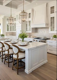 a large kitchen with white cabinets and wooden flooring, along with an island in the middle