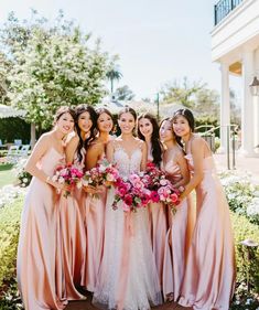 a group of women standing next to each other in front of some bushes and flowers