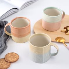 two coffee mugs sitting next to each other on a plate with spoons and cookies