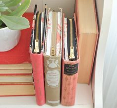 three books are stacked on top of each other near a potted plant