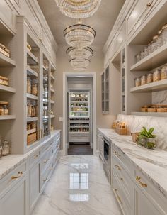 an elegant kitchen with marble counter tops and white cabinets, chandelier hanging from the ceiling