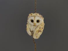 an owl ornament hanging from a rope on a gray background with beads and crystals