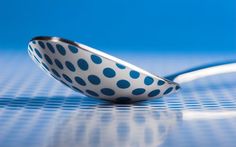 a blue and white polka dot bowl with a spoon resting on the table next to it