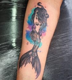 a woman's arm with a mermaid tattoo on it