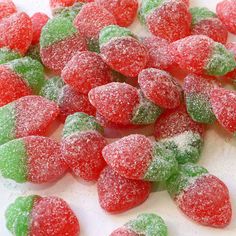 there are many small candy hearts on the white tablecloth with green and red candies