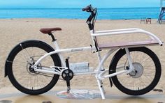 a white bike parked on top of a sandy beach