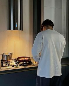 a man standing in front of a stove top oven next to a pan with food on it