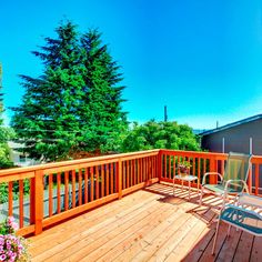 a wooden deck with chairs and trees in the background