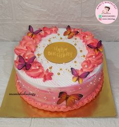 a birthday cake with pink flowers and butterflies on it's icing, sitting on top of a gold plate