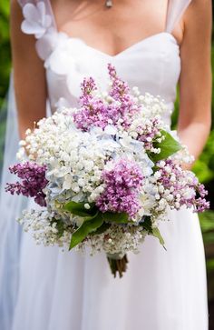 a bride holding a bouquet of purple and white flowers