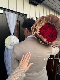 a man and woman standing next to each other in front of a door with flowers on it