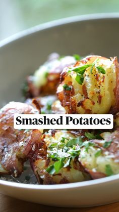 a white bowl filled with potatoes covered in parmesan cheese and garnished with herbs