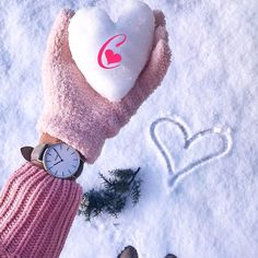 a person holding a heart shaped pillow in the snow with a watch on their wrist