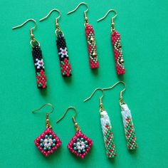 six pairs of beaded earrings sitting on top of a green surface