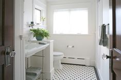 a white bathroom with black and white floor tiles