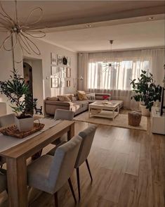 a living room filled with furniture next to a wooden table and white walls in front of a window