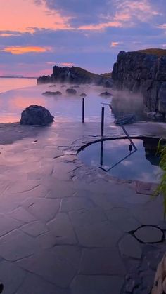 a hot tub sitting on top of a sandy beach next to the ocean at sunset