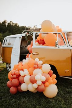 an orange and white vw bus with balloons in the back