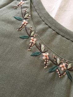 an embroidered t - shirt with flowers and leaves on it