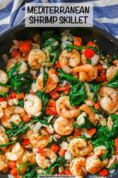 a skillet with shrimp, spinach and carrots in it on a blue towel