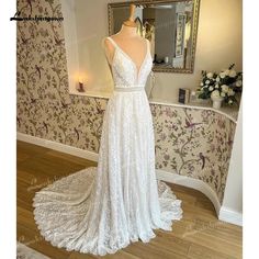 a white wedding dress on display in front of a floral wallpapered room with a mirror