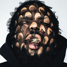 a man with his mouth covered in black and gold circles on it's face