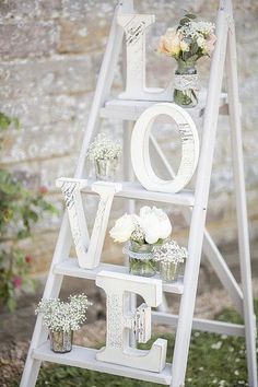 a white ladder decorated with flowers and the word love spelled out on it's side