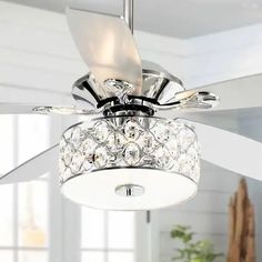 a white ceiling fan with crystals on it in a living room or dining room area