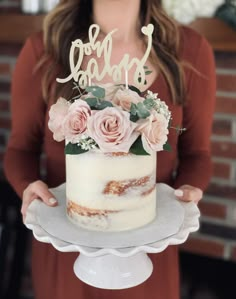 a woman holding a cake with flowers on it and the word love is spelled in cursive letters