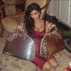 a woman sitting on the floor holding two purses