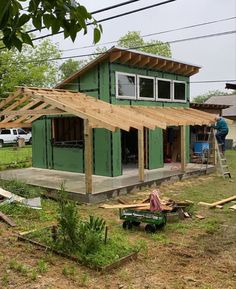 a house being built in the middle of a yard with wood framing on top of it