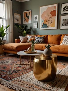 a living room with orange couches and pictures on the wall above it, along with potted plants