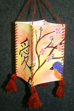 an open book with chinese writing on it hanging from a string and decorated with tassels