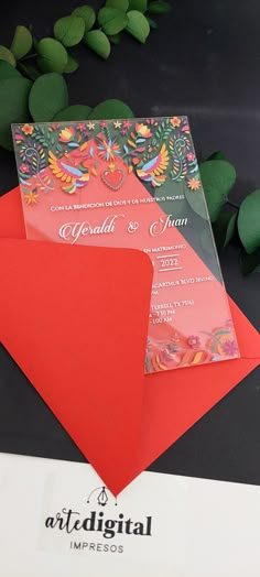 two red envelopes are sitting next to each other on a table with greenery