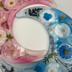 a pink and blue moon with flowers on it's side sitting on a plate