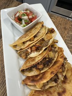 a white plate topped with tortillas next to a bowl of salad