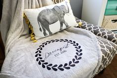 an elephant pillow sitting on top of a chair next to a bed with a blanket