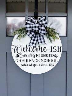 a welcome sign hanging on the front door of a school with an evergreen wreath around it