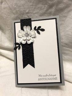 a close up of a card with a ribbon and flower on the front, in black and white