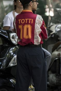 a man standing next to a motorcycle wearing a jacket with the number 10 on it