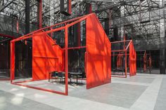 an empty room with red walls and chairs in the center, surrounded by metal structures