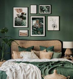 a bedroom with green walls and pictures on the wall above the bed, along with wicker baskets