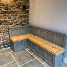 a corner bench with built - in storage underneath it on a stone floor next to a brick wall