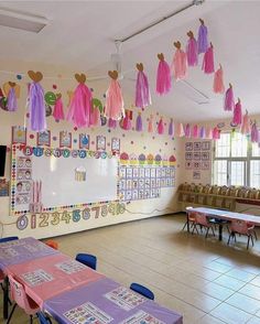 a classroom with tables, chairs and decorations hanging from the ceiling