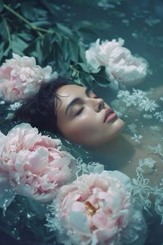 a woman laying in the water surrounded by flowers