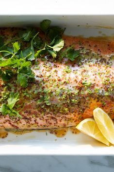 a close up of a fish on a plate with lemons and parsley